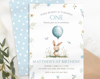 Puede incluir: Un sobre de lunares azules y blancos con una tarjeta blanca en su interior. La tarjeta tiene una ilustración de acuarela de un conejito sosteniendo un globo azul. El texto de la tarjeta dice: "Some bunny is turning one. Please join us to celebrate. Matthew's 1st Birthday. Sunday | April 14 | 3 PM. 123 Happy Lily Lane, San Diego, CA 12345. RSVP to Mom 123-456-7890. Happy Lily Prints."
