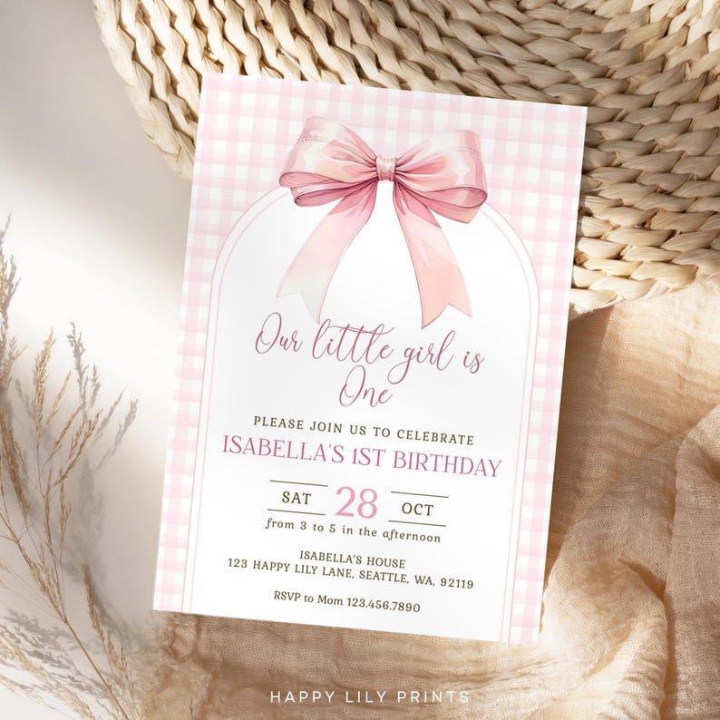 May include: Pink and white gingham patterned invitation with a large pink bow. The text reads "Our little girl is One. Please join us to celebrate Isabella's 1st Birthday. Sat 28 Oct from 3 to 5 in the afternoon. Isabella's House 123 Happy Lily Lane, Seattle, WA, 92119. RSVP to Mom 123.456.7890. Happy Lily Prints."