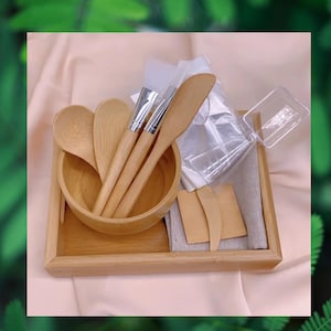 Op de afbeelding: Een houten dienblad met een set houten gereedschap voor het aanbrengen van gezichtsmaskers. De set bevat een kom, lepels, spatels en kwasten.