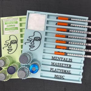 May include: A light blue organizer with multiple compartments, holding syringes with orange caps. The organizer also features a section for alcohol pads and vials. The words "MENTALIS", "MASSETER", "PLATYSMAL", and "MISC" are printed on the organizer.