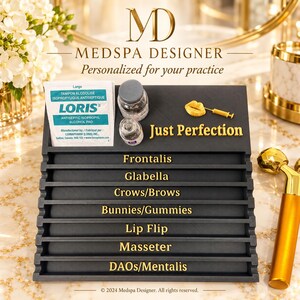 May include: A black tiered display stand with gold lettering labeled Frontalis, Glabella, Crows/Brows, Bunnies/Gummies, Lip Flip, Masseter, and DAOs/Mentalis. It includes a Loris alcohol pad, two small glass vials, and a gold lip-shaped charm.