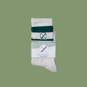 May include: White hemp socks with green stripes and a green logo of two crossed skateboards in a circle. The logo says "Doc Flossin's Hemp Socks".