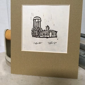 May include: A black and white linocut print of a water tower and a building. The print is signed "Coffee Pot" and "Jefferson".