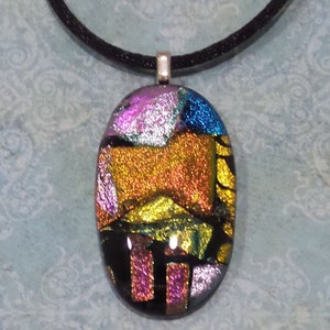 May include: A colorful oval glass pendant with a black cord. The pendant features a mosaic of iridescent glass in shades of pink, gold, blue, and green.