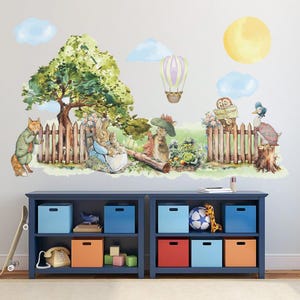 Puede incluir: Un vinilo decorativo de pared caprichoso que representa una escena de cuento de hadas con animales de dibujos animados, un árbol, una valla y un globo aerostático. La escena incluye un zorro, conejos y un pato. El fondo tiene un sol amarillo y nubes azules.