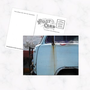 Può includere: Un furgone vintage blu con striature di ruggine sul lato, parcheggiato contro un muro rovinato. Il furgone ha un paraurti nero e uno scalino laterale nero.