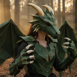 May include: A green dragon costume featuring a geometric mask with cream-colored horns, matching segmented chest armor, large angular wings, and clawed gauntlets. The structure is composed of faceted panels with visible edges, creating a sharp, angular appearance across the head, torso, and hands.