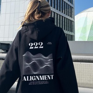 May include: Black hoodie with a graphic design on the back. The design features a wavy pattern with the text "222" and "ALIGNMENT".