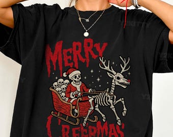 May include: Black t-shirt featuring a skeletal Santa Claus in a sleigh pulled by a skeleton reindeer. The design includes the text "Merry Creepmas" in red, gothic-style lettering. The shirt is a relaxed fit.