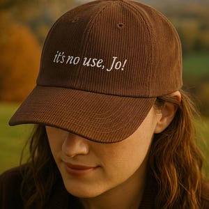 Puede incluir: Una gorra de béisbol de pana marrón con bordado blanco que dice "it's no use, Jo!"