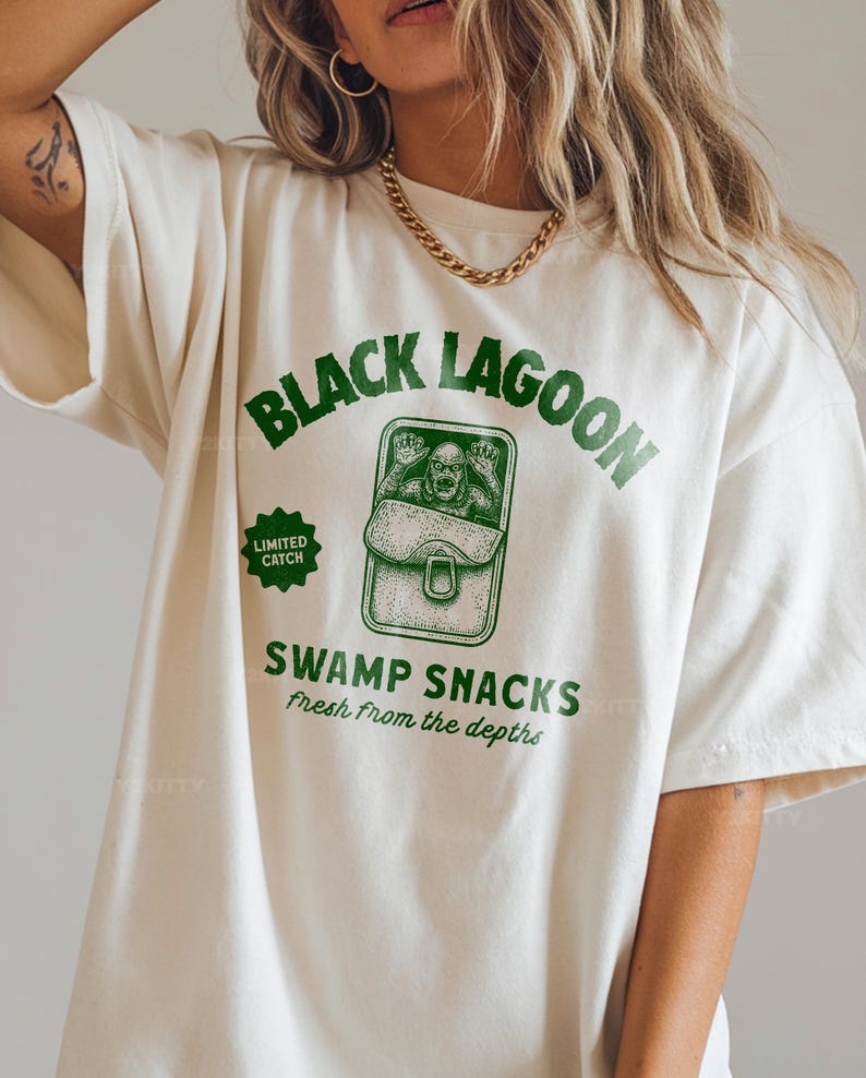 May include: Off-white t-shirt with a green graphic that reads "BLACK LAGOON SWAMP SNACKS Fresh From the Depths." The graphic features a creature in a can. The shirt also has a "LIMITED CATCH" badge.