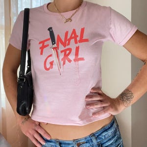 May include: Pink cropped t-shirt with a red graphic of a knife and the text "FINAL GIRL".