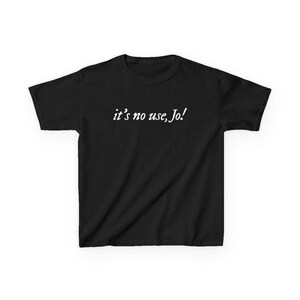 May include: A black t-shirt with the white text "it's no use, Jo!" printed across the chest. The shirt has short sleeves and a crew neck. The text is in a cursive font.