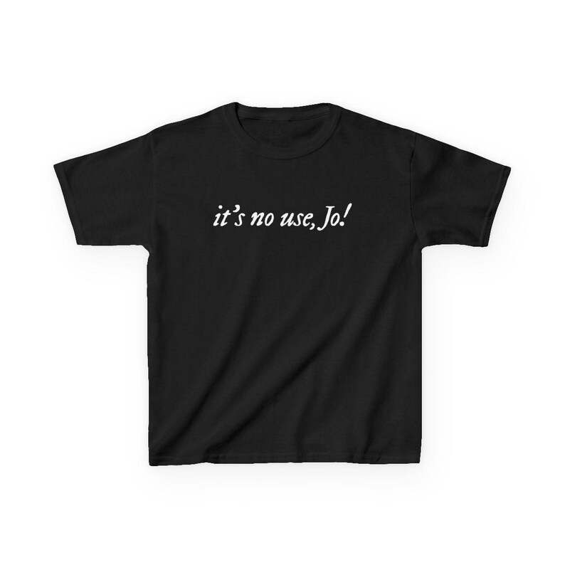 May include: A black t-shirt with the white text "it's no use, Jo!" printed across the chest. The shirt has short sleeves and a crew neck. The text is in a cursive font.