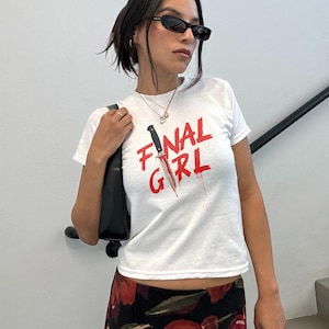 May include: White t-shirt with a red graphic of a knife and the text "FINAL GIRL".
