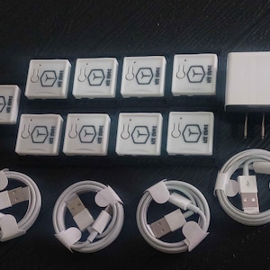 Puede incluir: Un conjunto de dispositivos y accesorios electrónicos blancos, que incluyen varias unidades cuadradas pequeñas con el texto "ICE CURE" y un logotipo, un adaptador de corriente y varios cables USB blancos enrollados.