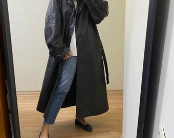 May include: A long black leather trench coat with a belt. The coat has a button closure and a collar.