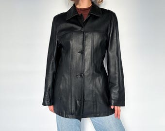 Könnte beinhalten: Eine schwarze Lederjacke mit Knopfleiste und Kragen. Die Jacke hat eine figurbetonte Silhouette und ist aus glattem, geschmeidigem Leder gefertigt.
