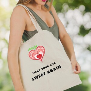 May include: A white canvas tote bag with a red heart design and the text "Make your life sweet again".
