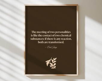 May include: A framed print with a dark brown background features a quote by Carl Jung in a light beige font. The quote reads, "The meeting of two personalities is like the contact of two chemical substances: if there is any reaction, both are transformed."