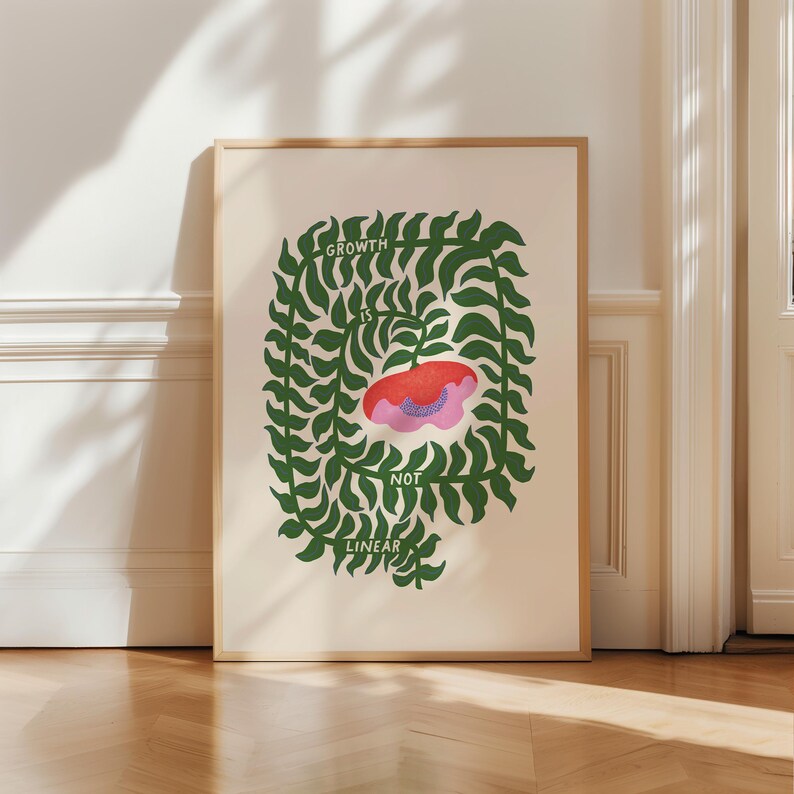 May include: A framed art print with the text "GROWTH IS NOT LINEAR." The artwork features a red and pink floral shape at the center, surrounded by a green leafy border. The background is a light beige color.