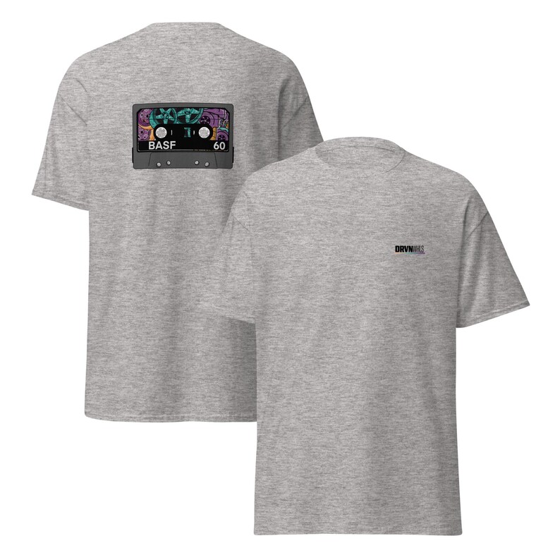 Puede incluir: Dos camisetas de color gris jaspeado. Una camiseta presenta un gr&aacute;fico de cinta de cassette colorida en la parte posterior con el texto "BASF 60". La otra camiseta tiene el texto "DRVN" impreso en la parte delantera.