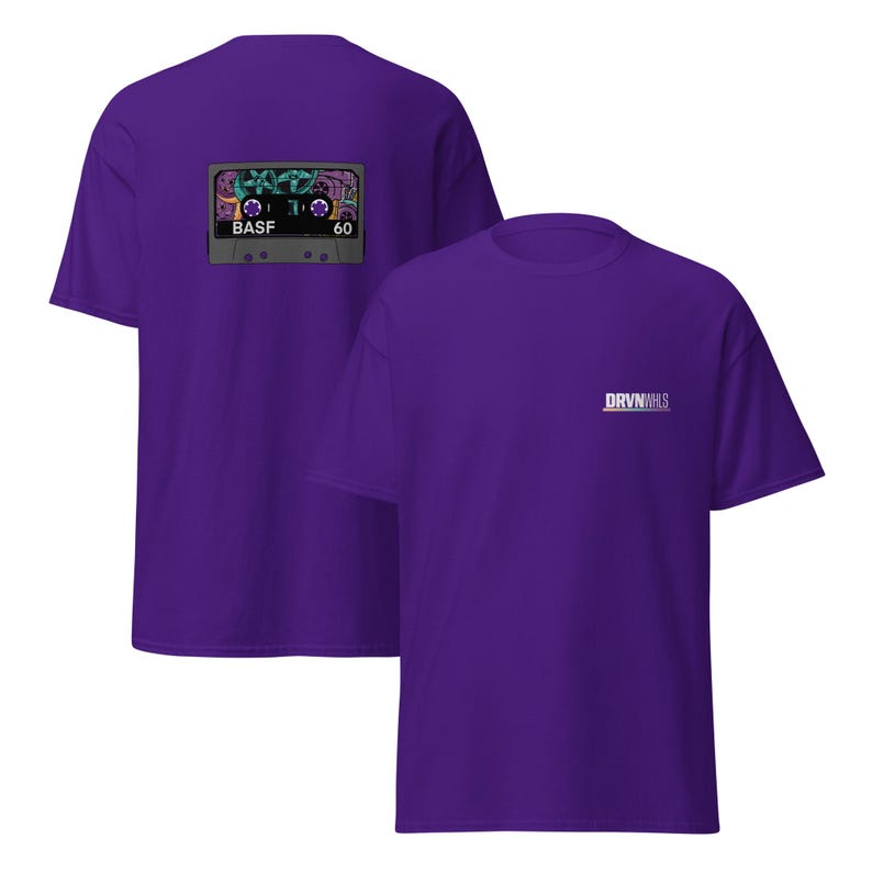 Puede incluir: Dos camisetas moradas. Una camiseta presenta un gr&aacute;fico de cinta de cassette en la espalda con el texto "BASF" y "60". La otra camiseta tiene el texto "DRVN VHS" en la parte delantera. Las camisetas son de tejido suave.