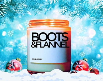 May include: A candle in a glass jar with a white label that says "Boots & Flannel" and "Tomey & Rod". The candle is surrounded by a snowy background with red and white ornaments and a blue and white wintery background.