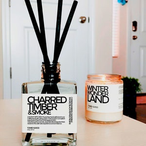 May include: A clear glass diffuser bottle with black reeds and a label that reads "Charred Timber & Smoke"  Ascent Diffuser.  A candle in a clear glass jar with a white label that reads "Winter Wonder Land" Tomey & Rod.