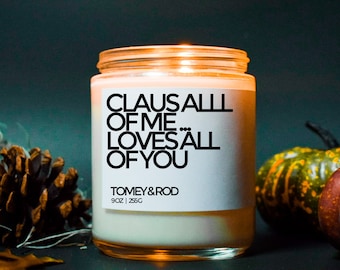May include: A white candle jar with a black label that reads "Claus all of me loves all of you". The label also includes the brand name "Tomey & Rod" and the size "9 oz | 256g".