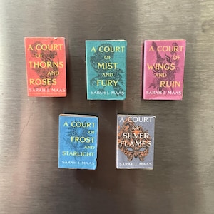 Puede incluir: Un conjunto de cinco portadas de libros para la serie "A Court of Thorns and Roses" de Sarah J. Maas. Las portadas son de varios colores, incluyendo rojo, azul y rosa, y presentan diferentes ilustraciones. Los títulos de los libros son "A Court of Thorns and Roses", "A Court of Mist and Fury", "A Court of Wings and Ruin", "A Court of Frost and Starlight", y "A Court of Silver Flames".