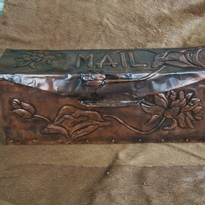 May include: A copper mailbox with a floral design and the word "MAIL" embossed on the front.