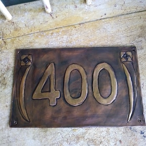 May include: A copper house number plaque with the number 400 embossed in gold. The plaque has a decorative design on each side.