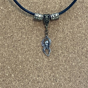 May include: A black leather necklace with silver and bronze beads and a silver spider pendant.