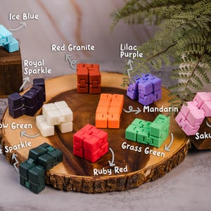 May include: A wooden tray with 10 colorful fidget cubes, each with a different color and name. The colors include ice blue, royal sparkle, red granite, lilac purple, glow green, alpine sparkle, mandarin, grass green, ruby red, and sakura pink.