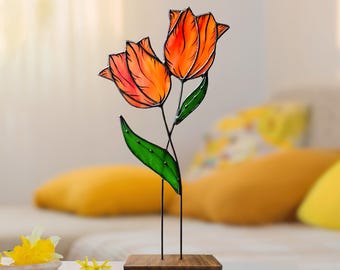May include: A stained glass sculpture of two orange tulips with green leaves on a wooden base.