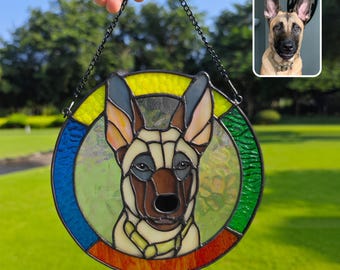 May include: A stained glass window hanging with a black chain. The window is round and features a colorful design with a dog's face in the center. The dog is a light brown and white with a black nose and dark eyes.