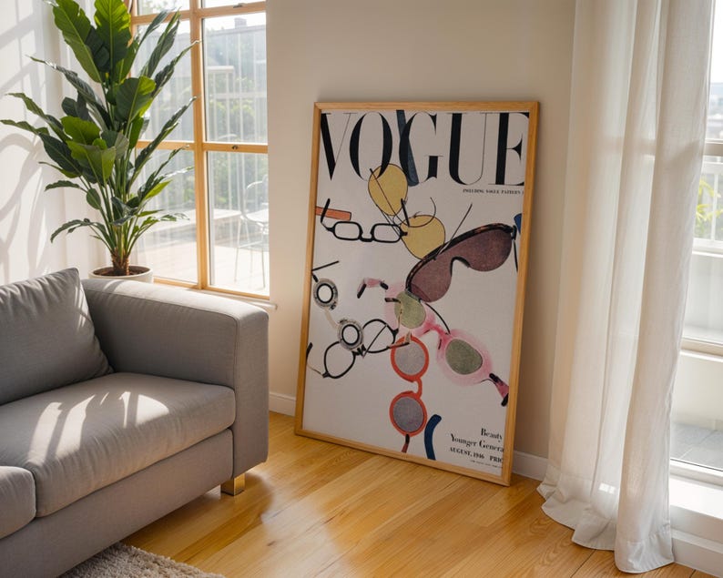 May include: A framed vertical poster featuring a vintage Vogue magazine cover from August 1936. The artwork displays a white background with the black text VOGUE at the top and various colorful illustrations of eyeglasses and sunglasses scattered throughout.