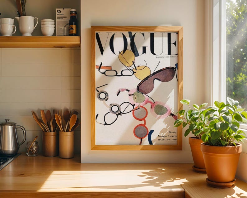 May include: A framed Vogue magazine cover print from August 1996 featuring a white background with various colorful illustrations of eyeglasses and sunglasses scattered across the page. The frame is made of light-toned wood and hangs on a wall.