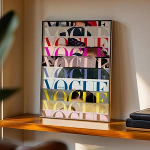Op de afbeelding: Een ingelijste display van Vogue-magazinecovers. De covers zijn verticaal gestapeld en tonen verschillende internationale edities met kleurrijke tekst en afbeeldingen. De lijst is goudkleurig en de display staat op een houten plank.