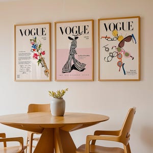 May include: Three framed Vogue magazine covers displayed on a wall. The left print features a floral bouquet, the centre print shows a striped dress on a pink background, and the right print displays various colourful eyeglasses and sunglasses.
