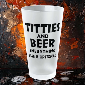 May include: White frosted glass beer mug with black text that reads "TITTIES AND BEER EVERYTHING ELSE IS OPTIONAL".