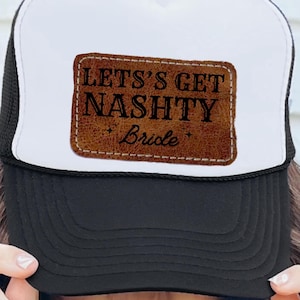 Puede incluir: Gorra de camionero blanca y negra con un parche de cuero marrón que dice "Let's Get Nashy Bride".