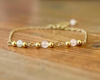 May include: A delicate gold chain bracelet with alternating light blue and pink beads.