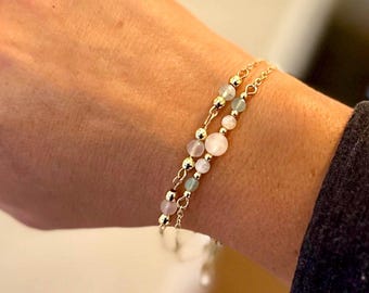 May include: Two gold chain bracelets with light pink and light blue beads.