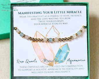 May include: A gold beaded bracelet with rose quartz, moonstone, and aquamarine gemstones. The card behind the bracelet reads "Manifesting Your Little Miracle" and mentions hope, patience, and trust. The crystals are used to support fertility and wellness during pregnancy.