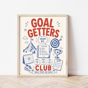 May include: A framed poster with a cream background featuring red and blue illustrations and text. The text reads GOAL GETTERS CLUB, DREAM BIG, and SMALL STEPS. BIG GOALS. Graphics include a mountain, target, trophy, calendar, and checklists.