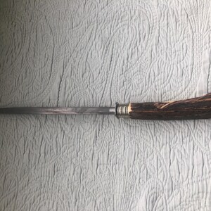 May include: A knife with a long, slender, silver blade and a handle made of brown antler material. The handle is secured with silver metal rings. The knife is designed for cutting and slicing.