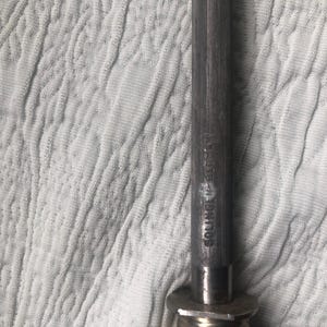 May include: Close-up of a metal knife sharpener with the text "SOLINGEN GERMANY" etched on the side. The sharpener has a dark, textured handle and a metal base. The background is a white, textured fabric.