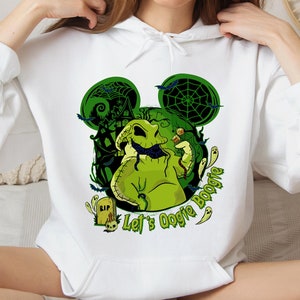 May include: White hoodie featuring a green Oogie Boogie design with a haunted house, bats, and spiderwebs. The design includes the text "Let's Oogie Boogie" and ghost illustrations. A tombstone with "RIP" is also visible.